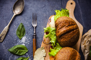 Fast food on the table: burger with beef or pork, or chicken and vegetables, French fries with tomato sauce, basil leaves