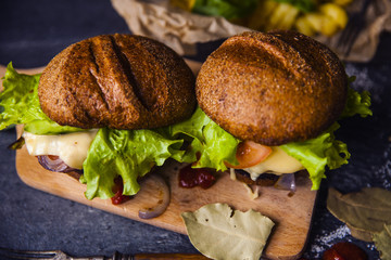Fast food on the table: burger with beef or pork, or chicken and vegetables, French fries with tomato sauce, basil leaves