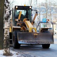 tractor cleans the road in the city of dirty snow
