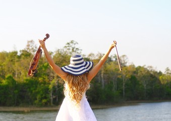 Woman in beautiful dress is happy with violin in forest