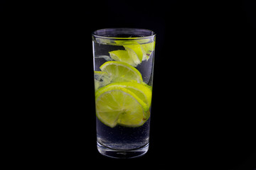 slices of lime in glass of water on black background