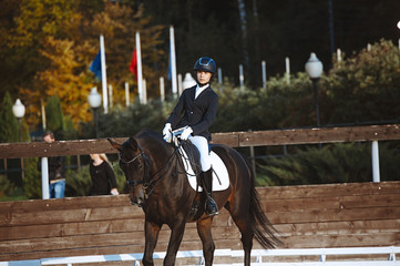 Young jockey brave girl rides on a horse show jumping. Rider on the horse sports competitions