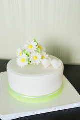 Beautiful light white wedding cake from the mastic with chamomile decor