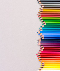 Multicolored pencils on beige pastel paper coarse grain grunge texture