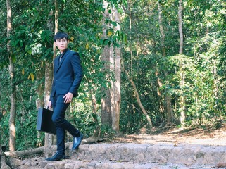 Young Asian businessman in black suit in the forest