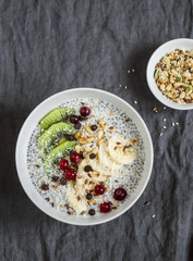 Chia pudding with fruits, seeds and nuts on a dark background, top view. Healthy breakfast or snack