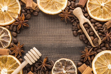 Orange slices with coffee, cinnamon, star anise and honey dipper on wooden background. Copy space