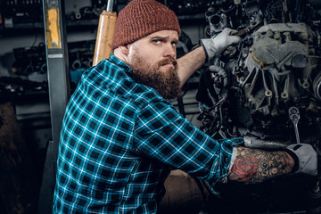 Obraz na płótnie Canvas Mechanicl inspecting engine of a car in a garage.