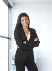 corporate portrait of young attractive latin business woman wearing formal suit smiling happy