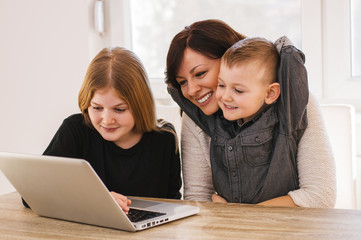 Happy loving family. Mom and kids playing on computer at home.