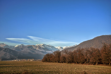 Fototapeta premium Scenic view of mountains, autumn or winter landscape with colorful hills at sunset. Yellow meadows and snowy mountains of Azerbaijan Big Caucasus. Gabala Sheki