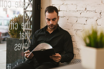 Handsome man at cafe checking menu. - Powered by Adobe