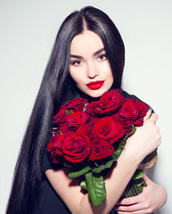 Beauty fashion model woman with big bouquet of red roses