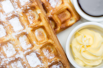 Whole wheat Belgium waffles on plate with butter, maple sauce close up. Top view