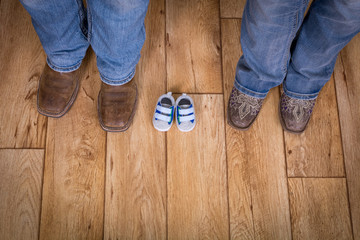 Mom and dad standing with baby shoes