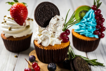 Chocolate cupcakes.Cupcakes with berries,fruit,strawberries. Top view.colorful cupcake,tasty cake,colorful cream,candies,cupcakes with summer berries on wooden background,close up,dessert concept
