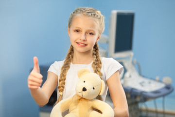 The girl with a soft toy in the hospital on a background of ultrasound machines, smiling and playing