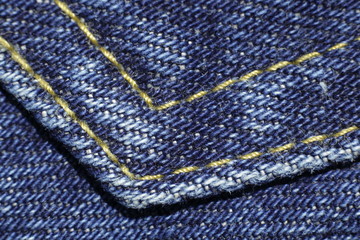 Blue denim material background with seam.  Textile clothing cotton jeans texture fabric closeup in studio.