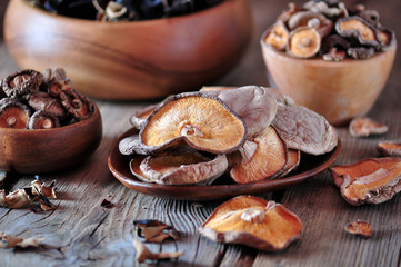 Various organic dried Chinese mushrooms in a wooden bowl on the old wooden background.