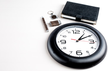 Collage. Lighter, key chain, notepad and pen are located next to the clock. White background.