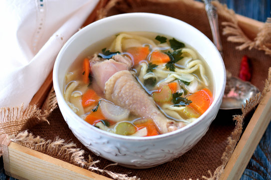 Soup with homemade noodles and organic chicken with carrots, root and leaves of parsley, onion and celery sticks.