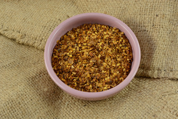 Crushed red pepper spice in pink condiment bowl on burlap