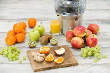 Modern electric juicer, various fruit and glass of freshly made juice, healthy lifestyle concept