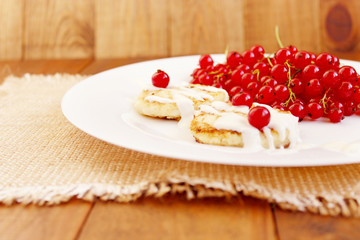 cheese cakes and berries of fresh red currant on the plate