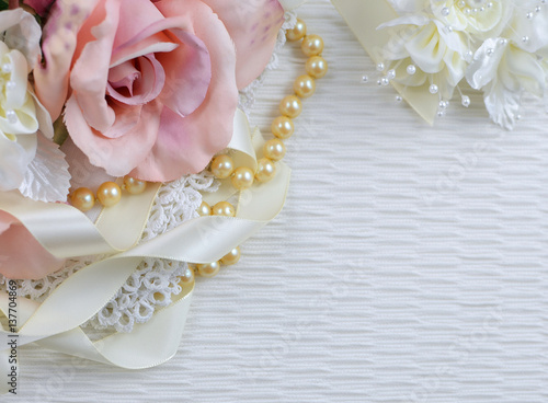 Silk Roses In A Pink Blush Color Arranged With Vintage Lace Pearls And Ivory Colored Satin Ribbon On Textured Fabric Background Silk Roses In A Pink Blush Color Arranged With Vintage Lace Pearls And Ivory Colored Satin Ribbon On Textured Fabric Background