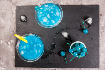 Party, cocktails blue lagoon or blue curacao on a slate tray on concrete stone table top view
