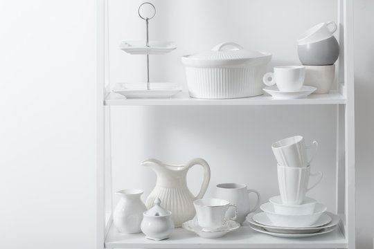 Clean dishes and vases on white wooden shelf © Maya Kruchancova