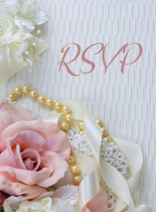 Silk roses in a pink blush color arranged with vintage lace, pearls, and ivory colored satin ribbon on a textured fabric background. Great image for wedding or engagement announcement. Text added.