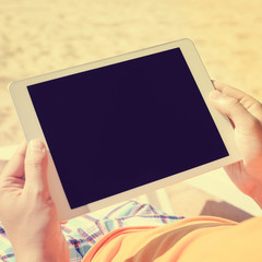 Businessman holding in hands using mobile tablet pc computer on sunny beach outdoors holiday. Top view mock up travel vacation background