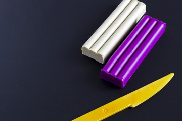 Colored Plasticine and knife on black background