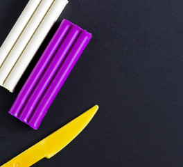 Colored Plasticine and knife on black background