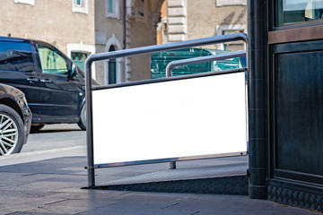 Information booth with blank billboard advertising panel on a street in the city Rome over blurred traffic on the road.