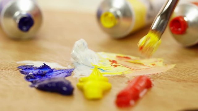 The woman mixes paints on a palette. White. Red. Blue. Yellow. Oil paints. Palette of paints. The artist prepares paints. White background. Close up