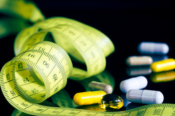Medical pills for healthy diet, vitamin tablets as a dietary supplement, measuring tape as a symbol...