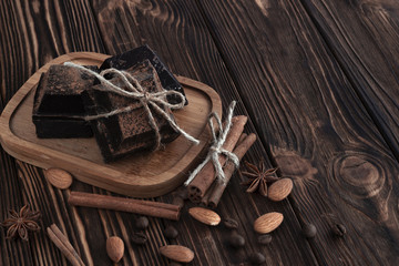 dark chocolate pieces  on wooden table with coffee bean, cocoa powder, cinnamon and star anise