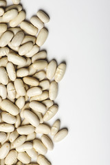 Background of white beans on the left side on white background. Isolated. Horizontal shoot.