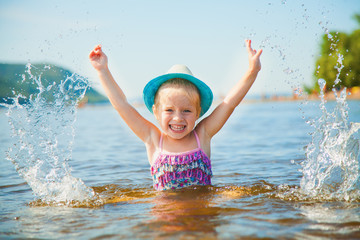 Fototapeta na wymiar Lovely baby girl making splashes in water. Summer hot day