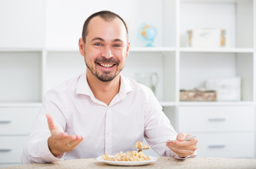 Positive young man eating porridge