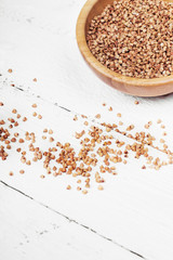 buckwheat in bowl isolated on white wooden background