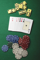 Letters and poker chips next to dominoes on green background. Vertical shoot.