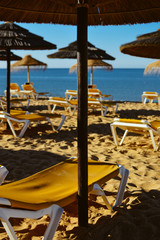 Straw umbrellas on ocean beach in Algarve Portugal, sunny outdoors background