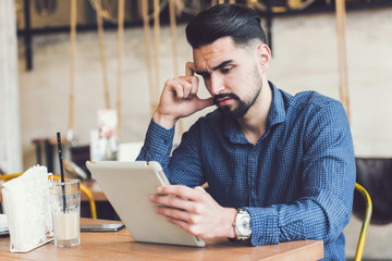 Catching up on some online news before work. Young businessman sitting in city cafe.