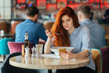 Young beautiful redhead woman eating vegetarian salad.