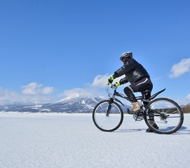 Fototapeta na wymiar 氷結の湖畔をマウンテンバイクで走る