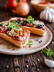 Baguette pizza with bacon, salami, cheese and vegetable