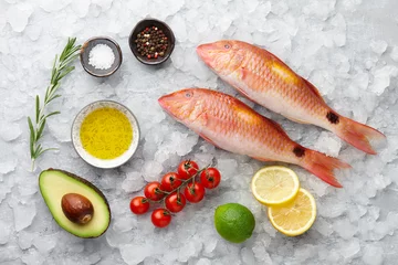 Papier peint photo autocollant rond Poisson Fresh red mullet fish with lemon, rosemary, avocado, chili pepper and spices on icy stone background
